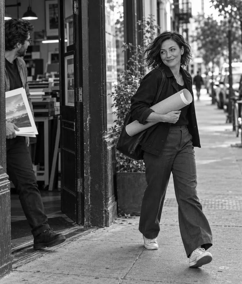 Maya leaving a print shop with project proofs under her arm.